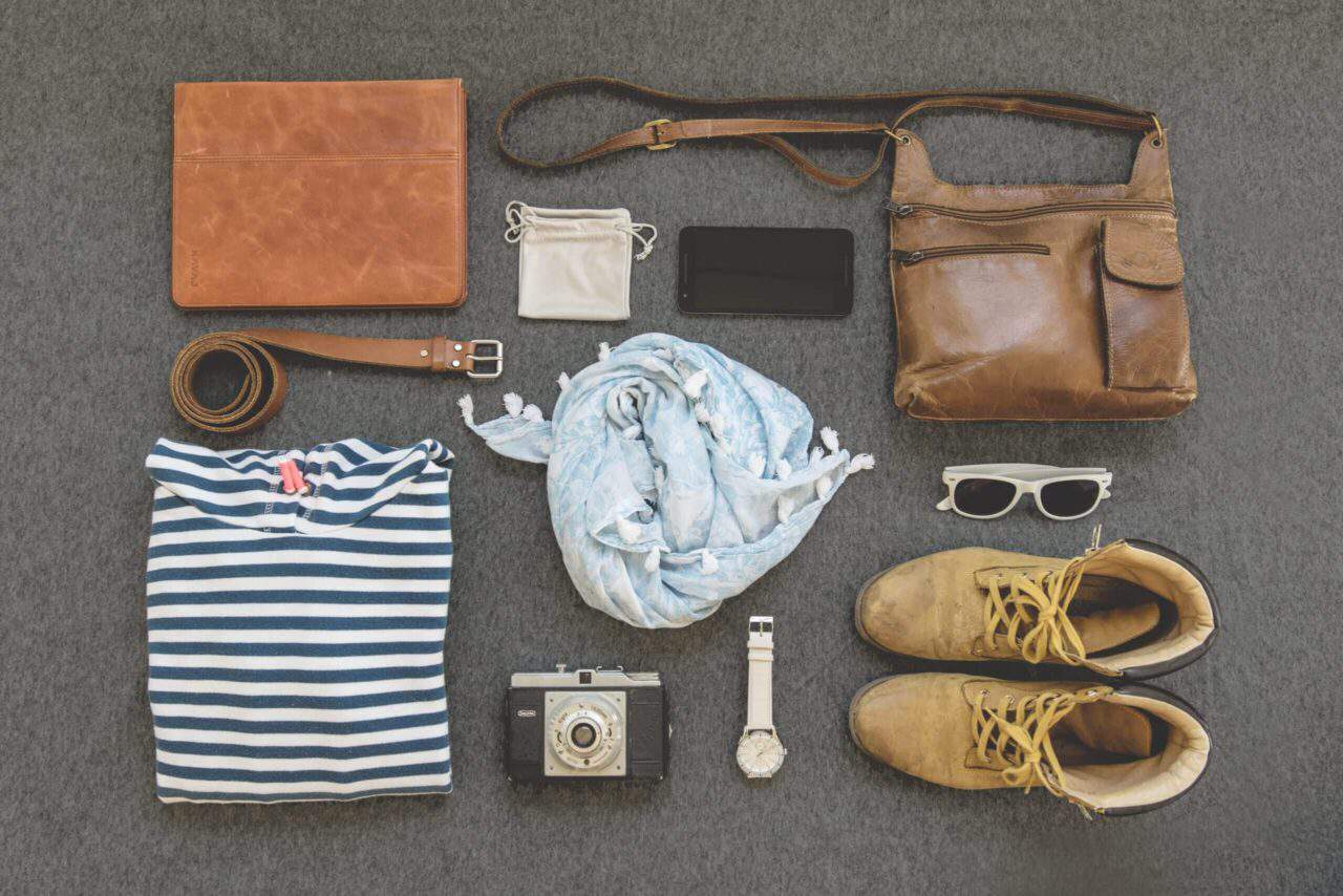 Sustainable clothing: shirt, scarf, belt, cellphone, bags, sunglasses, watch, camera, and boots.