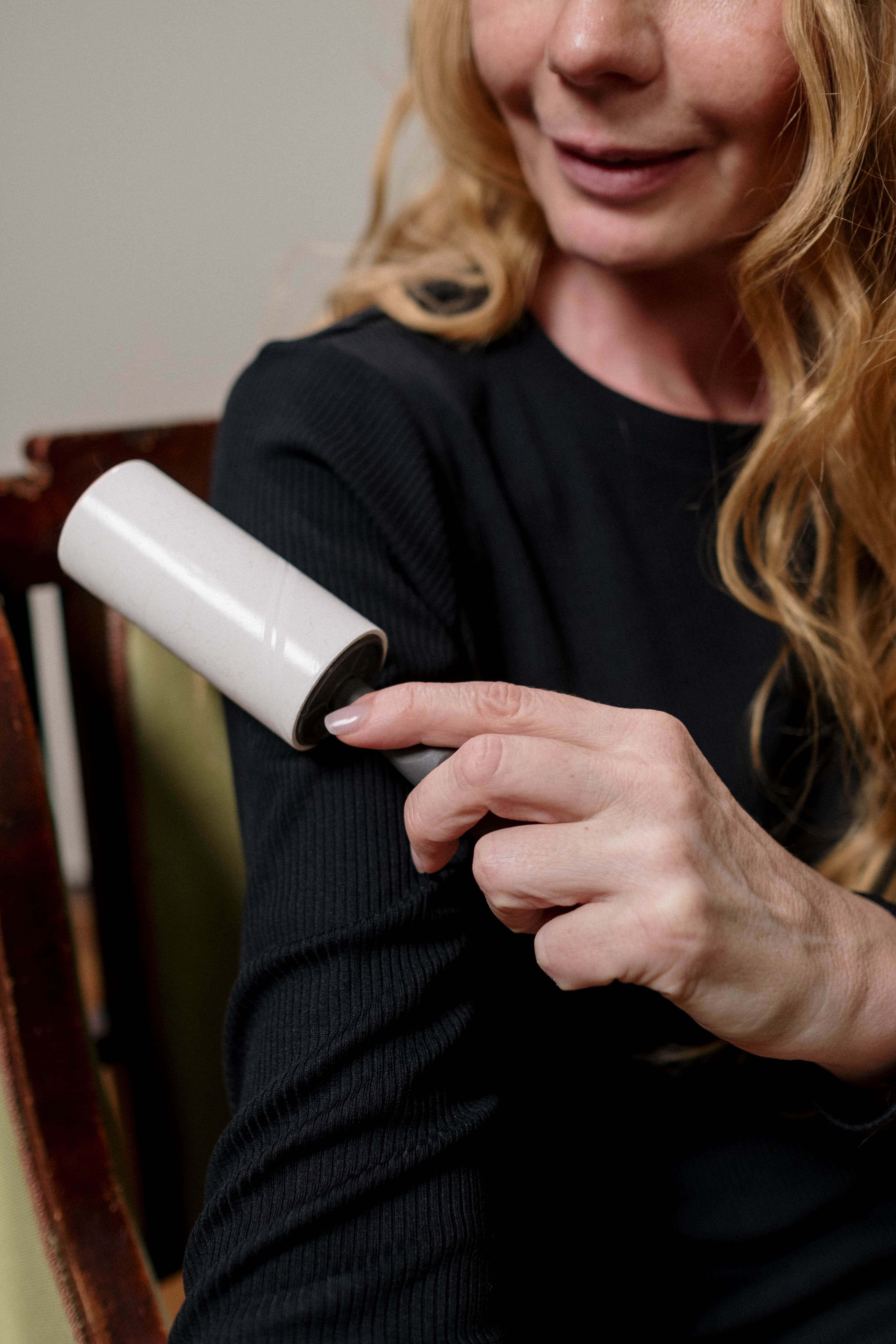 woman using lint roller on her sleeve