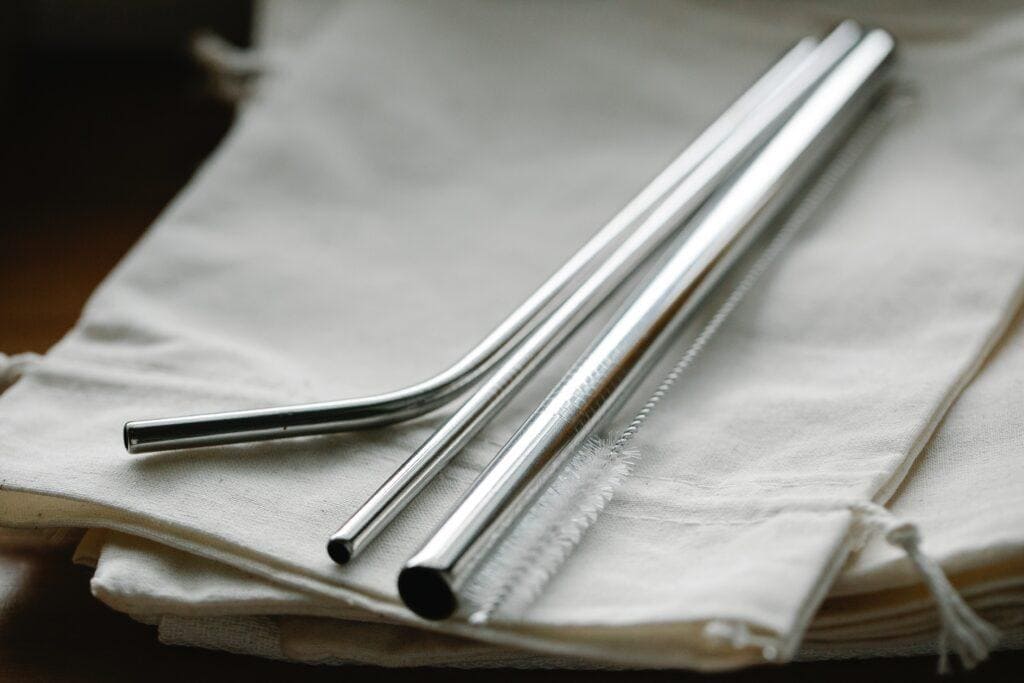 reusable metal straws and a straw cleaner lying on a napkin